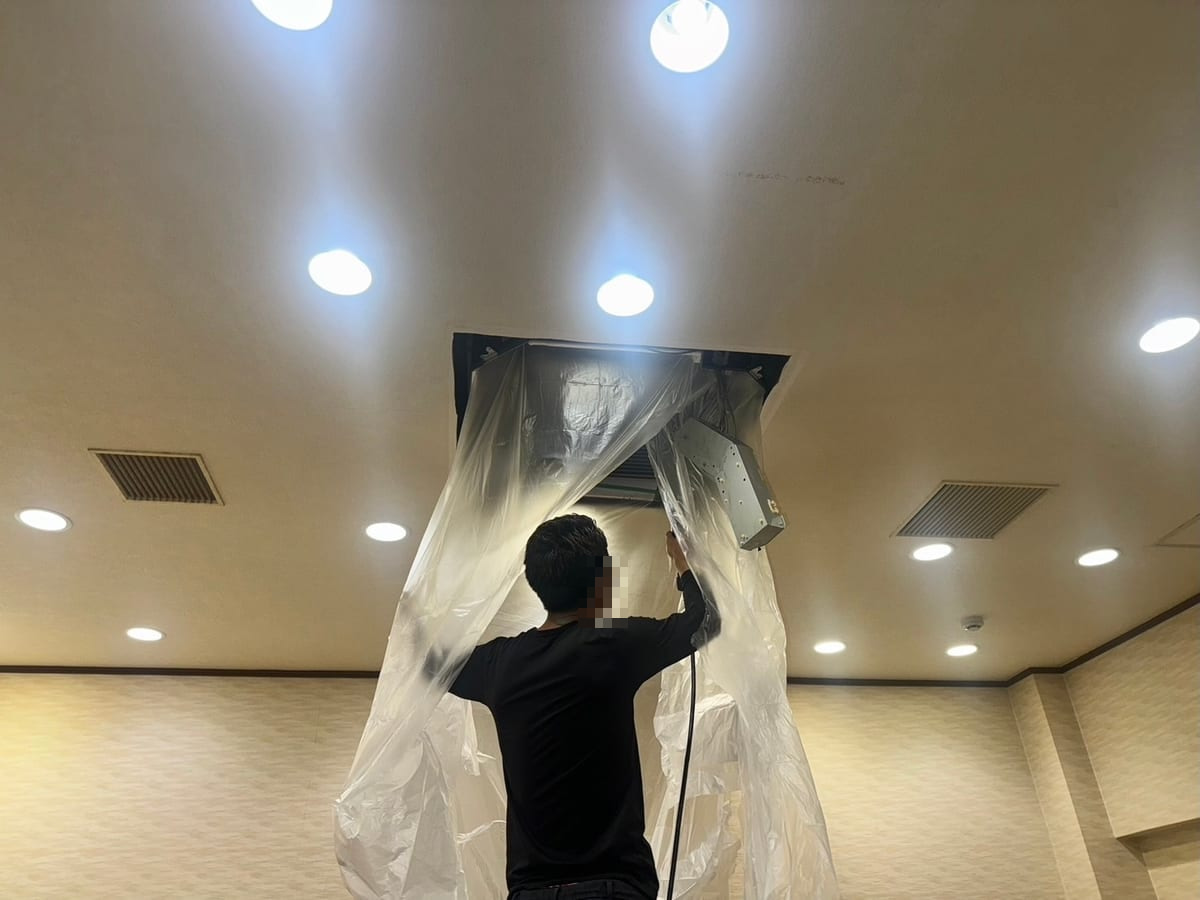 天井埋込形エアコンに洗浄用カバーを取り付ける作業者